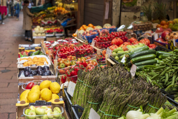 Traditional food market in the center of Bologna, Italy. Bundles of asparagus in the foreground.